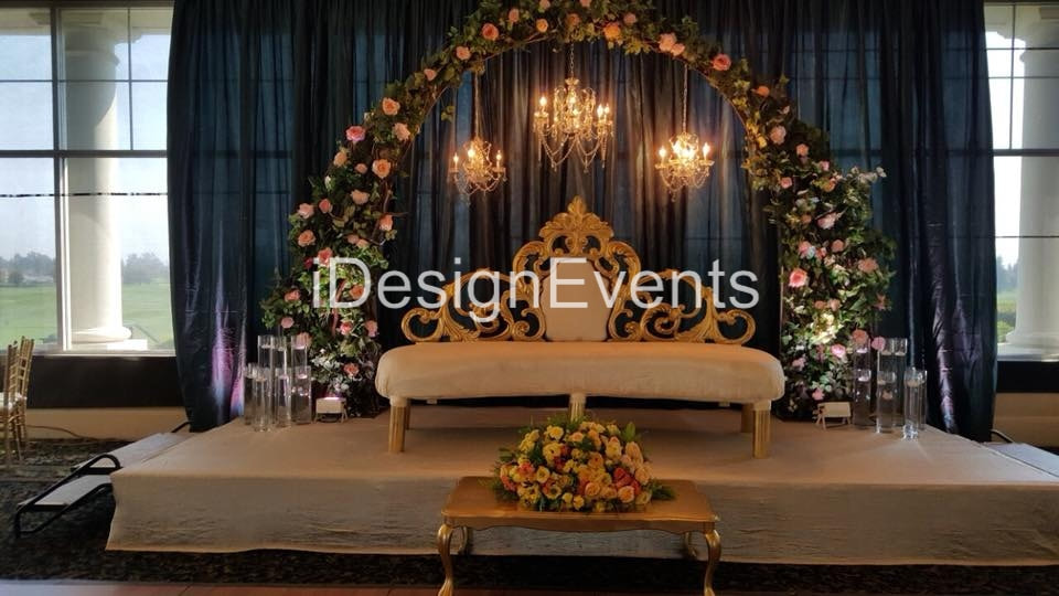 enchanted garden theme wedding reception decor arch with greenery and flowers with chandeliers and huge king loveseat forest by @idesignevents